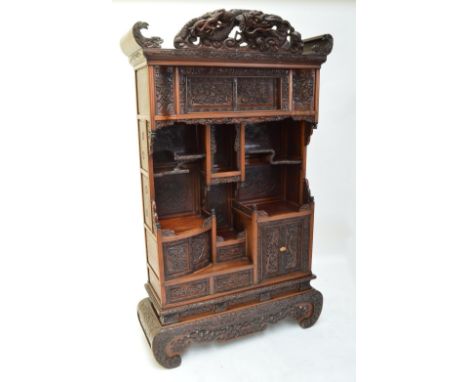 A Japanese Meiji period Shodhana cabinet, the pierced dragon adorned pediment above various stepped shelves, cupboard doors a