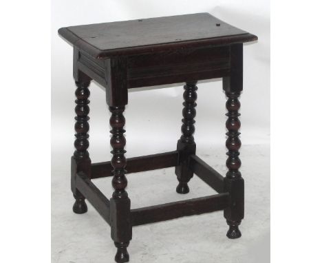 A 17th century oak joint stool with turned supports united by four plain stretchers and turned feet, height 55cm, width 44cm.