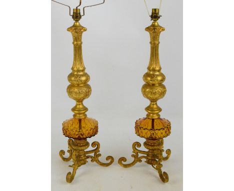 A pair of decorative gilt metal and amber glass table lamps with fluted and knopped stems, on scroll decorated tripod base, h