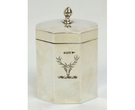 A George V hallmarked silver small octagonal tea caddy, the hinged lid with central finial, the body engraved with a crest of