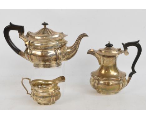 A matched early 20th century English hallmarked silver three piece tea service comprising a teapot of shaped oval form, lengt
