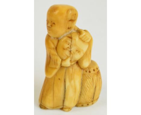 A Japanese Meiji period carved marine ivory netsuke modelled as a man holding a mask standing beside a drum, height 5cm.