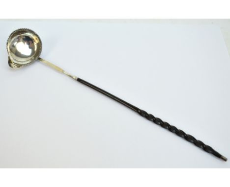 A Georgian hallmarked silver whale bone handled toddy ladle, the oval bowl with crimped rim and single lip, maker's initials 