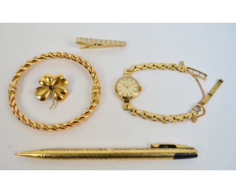 A 9ct yellow gold rope twist decorated snap bangle, a gold plated tie clip, yellow metal brooch in the form of a shamrock set