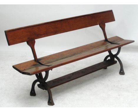 A pine and cast iron bench with pivotted back to allow seating either way, probably a railway bench, raised on cast iron cros