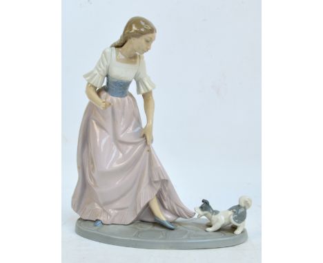 A Nao figure group depicting a girl with a dog pulling her dress, on oval base.