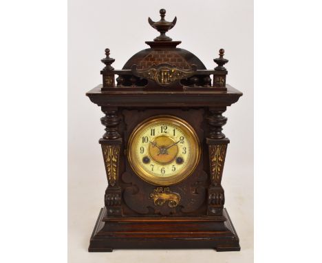 A c.1900 German stained beech mantel clock with Arabic numerals to the chapter ring flanked by scrolling pilasters and bearin