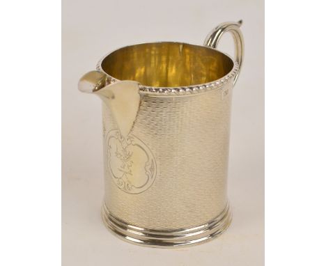 A Victorian hallmarked silver jug with overall engine turned decoration and loop handle, centred with a circular cartouche cr