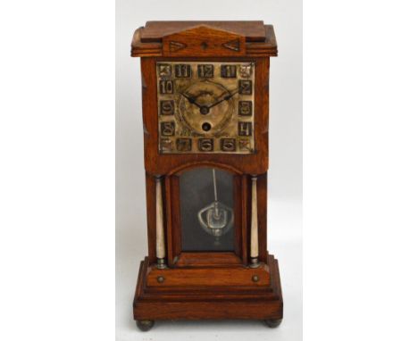 An Arts and Crafts mantel clock, the oak case set with embossed square section silvered dial with Arabic numerals and Jughans