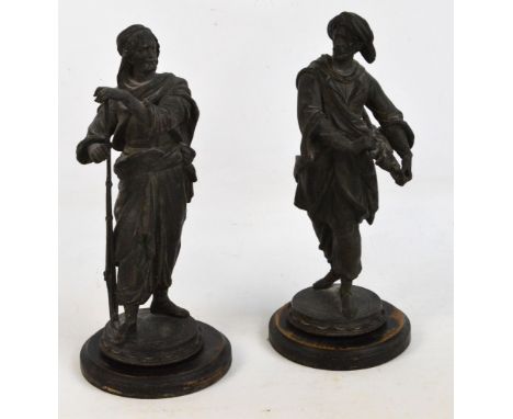 A pair of late 19th century spelter figures, one depicting a man carrying various swords, the second a man leaning on a gun, 