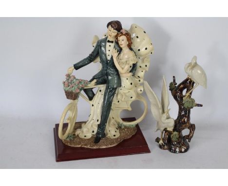A ceramic model depicting two cranes perching on a tree, approximately 24 cm (h) and a figural group depicting a couple sitti