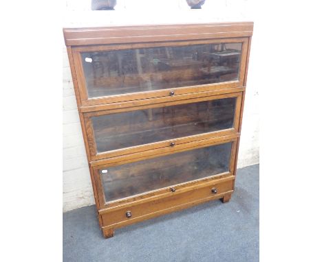 AN OAK GLOBE-WERNICKE BOOKCASE(non-metal type) three glazed sections with drawer beneath, with Bakelite knobs, on square feet