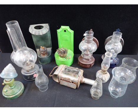 A COLLECTION OF TIN COTTAGE OIL LAMPSwall hanging (some lacking chimneys), a a carriage lamp, and other lamps and chimneys