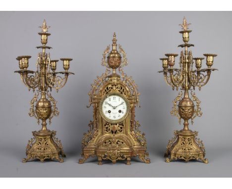 A Napoleon III style brass clock garniture. The clock dial stamped for G Sweron, Brussels, flanked by four branch candelabra.