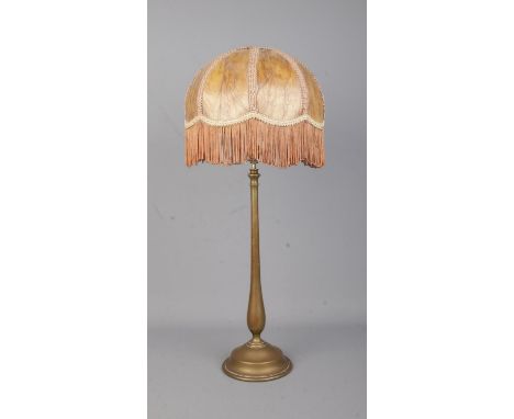 A brass rise and fall table lamp in the style of Benson with fringed shade.
