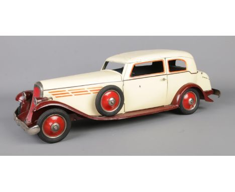 A large vintage sheet metal clockwork model car. Possibly by Paya. Length 50cm.  Missing battery for light up headlamps.