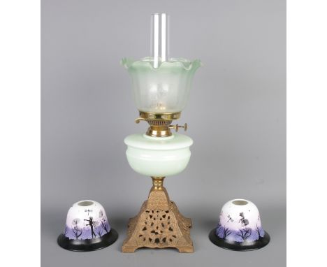 A Victorian green glass oil lamp along with a pair of glass light shades with hand-painted fairy scenes. Oil lamp with floral