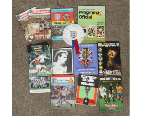 A collection of international football programmes and an England rosette. Includes 1966 World Cup final souvenir programme, E