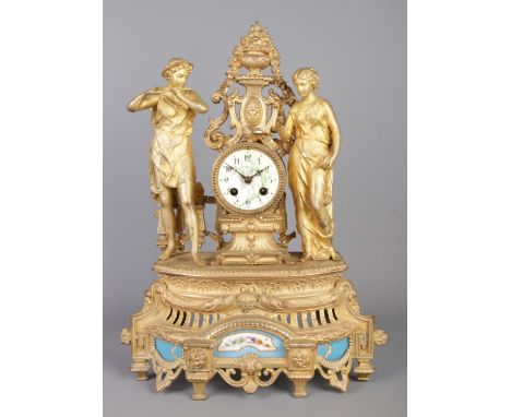 A French gilt metal figural mantel clock. Surmounted with a musician and a maiden and having Sevres style panels. Height 48.5