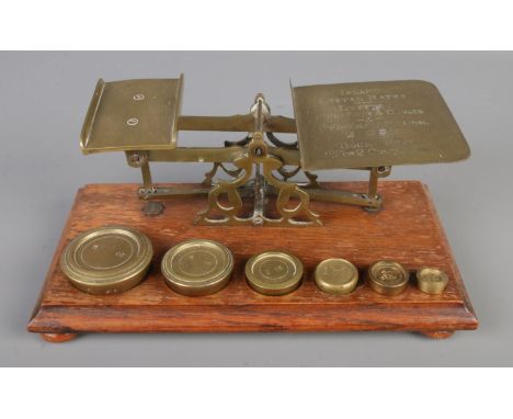 An antique brass "Inland Letter Rates" weighing scales on a wooden base, with sets of weights.