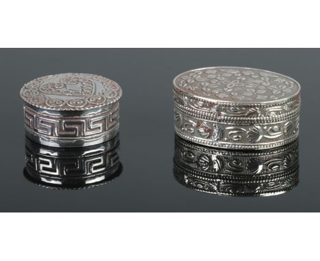 Two silver pill boxes. One with filigree style design and Greek key border, the other with engine turned engraving and foliat