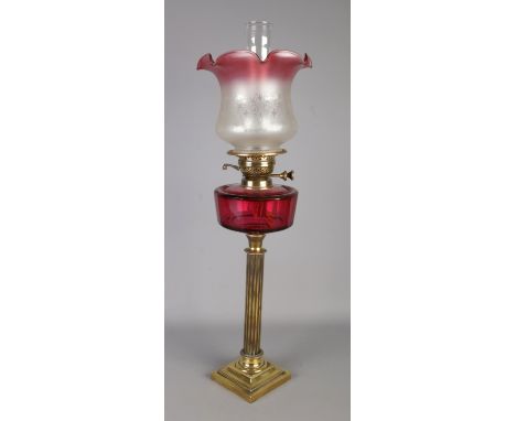 A tall Victorian cranberry glass oil lamp with florally etched cranberry glass shade, double brass burner and on a stepped sq