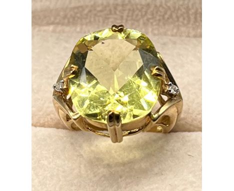 Large 9ct yellow gold ring set with a large green gem stone off set with round cut diamond stones to the shoulders. [Ring siz