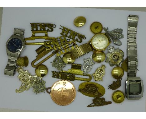 A collection of military cap and other badges, buttons and three wristwatches, including Rotary