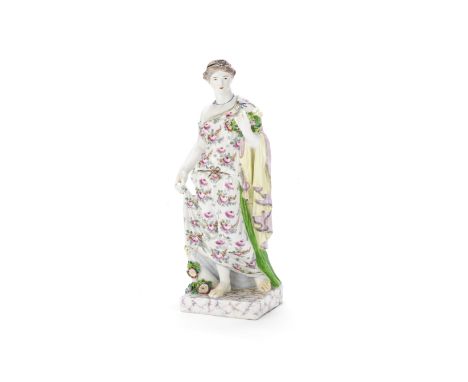 A large Bow figure of Flora, circa 1760The goddess standing beside a flowering stump, wearing a floral robe held up with her 