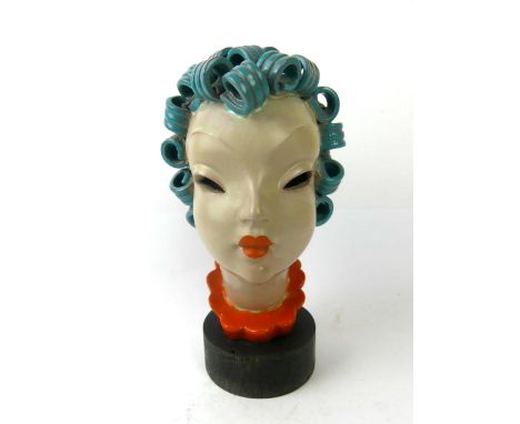 A Art Deco ceramic bustIn the style of Goldscheider, depicting a girl with blue curling hair, raised on turned wooden plinth 