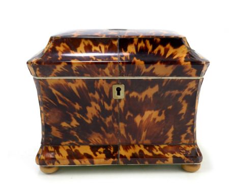 An early 19th century tortoiseshell and ivory two division sarcophagus tea caddy of waisted form, the hinged lid set with bra