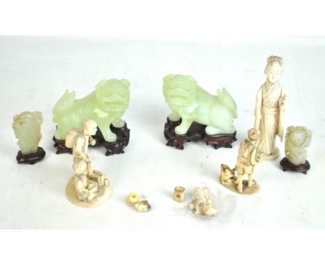 A pair of Chinese pale green Dogs of Fo, each on shaped hardwood stands, length 11.5cm, a small pair of carved figures and fo