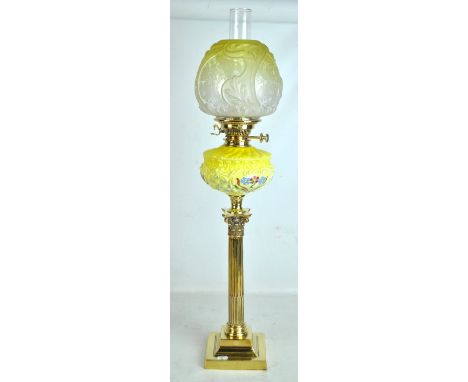 An Edwardian brass oil lamp with Corinthian stop fluted column beneath floral decorated reservoir and yellow tinted floral et