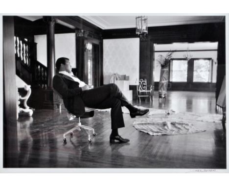 AFTER RALPH STARKWEATHER; a signed black and white print after the original photograph depicting Muhammad Ali sat in an offic