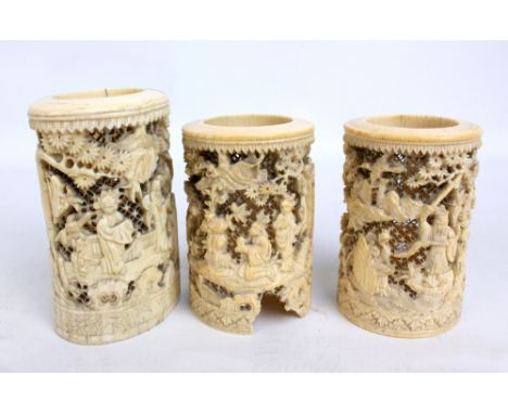 A pair of 19th century Chinese Canton carved ivory cylindrical vases elaborately decorated with architectural and figural lan