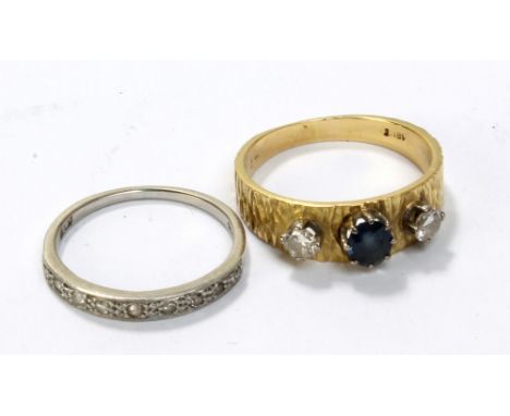 An 18ct yellow gold textured ring set with oval cut sapphire flanked by two round cut diamonds, each measuring approx 0.2ct, 