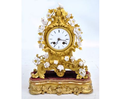 A French ormolu mantel clock with leaf and stem detail to white porcelain flowers, the circular dial set with Roman numerals 