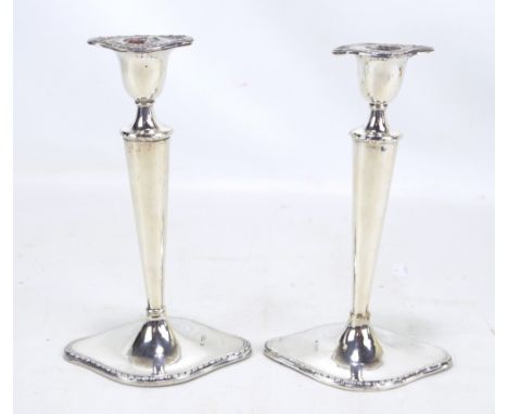 WILLIAM HUTTON & SONS LTD; a pair of Edward VII hallmarked silver candlesticks with tapering stems and shaped loaded bases, L