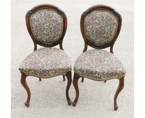 A set of four Victorian chairs with oval backs and stuffed over seats upholstered in floral tapestry