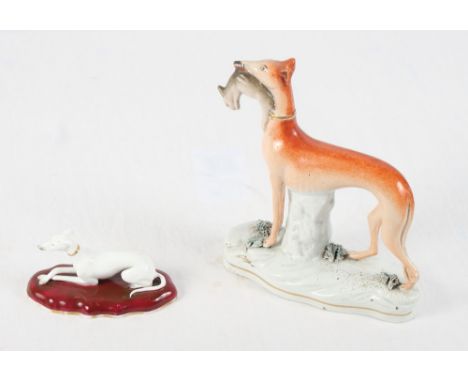 A mid 19th Century Staffordshire porcelain figure of a white greyhound on a red cushion (with sales receipt dated 1978) and a