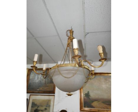 An early 20th century gilt metal six branch chandelier, with glass column, decorated with rams heads and swags 