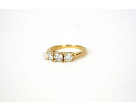 An unmarked yellow metal three stone diamond ring