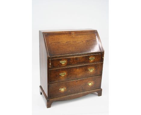 A George III oak bureau, the fall front opening to reveal a fitted interior, three drawers below with brass butterfly back pl