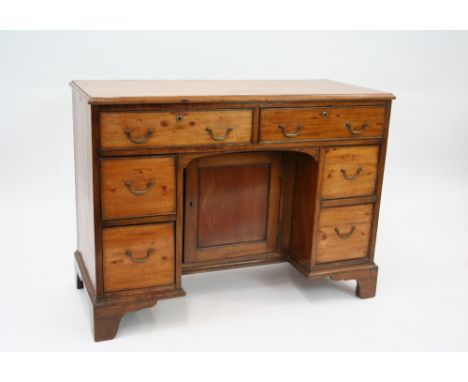 A Georgian mahogany kneehole writing desk, fitted two frieze drawers above a central cupboard, flanked by four smaller drawer