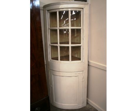 An unusual painted bow fronted corner cabinet, the upper section enclosed by a sash style sliding door, cupboard below, 90cm 