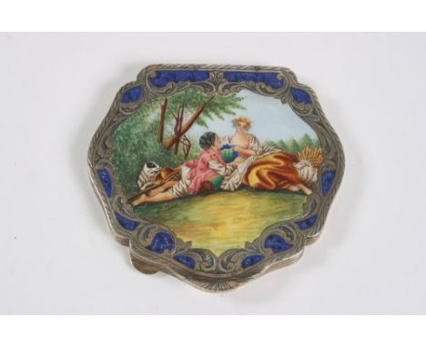 A large white metal and enamel decorated cartouche shaped compact, with Lapis coloured border and central panel of a romantic