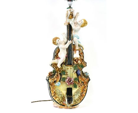 A large and unusual Capo de monte table lamp, in the form of a violin and climbing cherubs, having floral encrusted decoratio