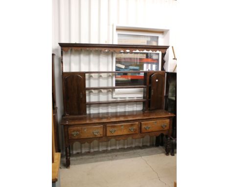 18th century Oak Dresser, the rack with carved shaped frieze, three open shelves and two cupboard doors, the base with three 