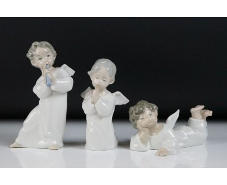Three Lladro porcelain figures of winged cherubs to include a cherub playing an instrument, cherub with hands clasped, and a 