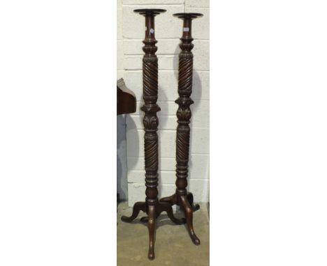 A pair of mahogany carved and turned bed posts converted as torchère stands, raised on tripod supports, 153cm high, (one with